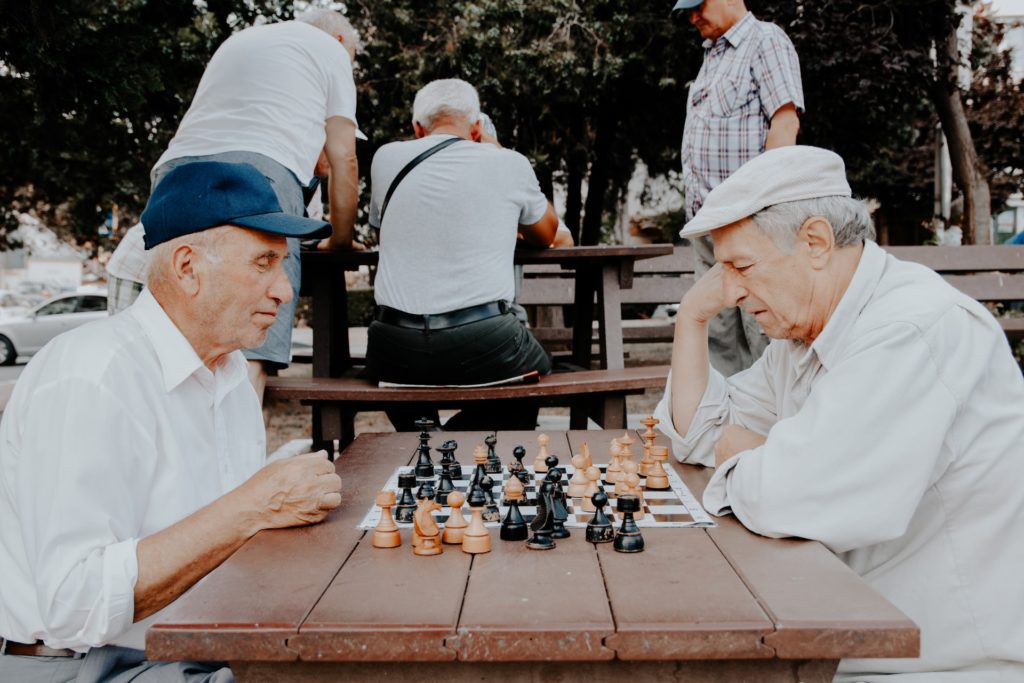 Two elderly gentleman playing chess outside